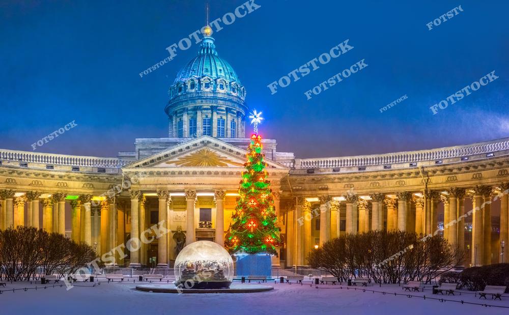 На фотографии изображён Казанский собор в Санкт-Петербурге, перед которым установлена нарядная новогодняя ёлка. Украшенная огнями и шарами, ёлка придаёт зданию торжественный и праздничный вид. Ночная иллюминация подчеркивает колоннаду собора, создавая неповторимую атмосферу зимнего праздника. Площадь вокруг собора покрыта снегом, что усиливает ощущение зимнего волшебства и притягивает жителей и туристов для праздничных фотографий.
